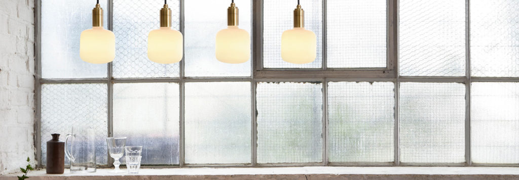 Four of Tala's sustainable light bulbs hanging in front of a window